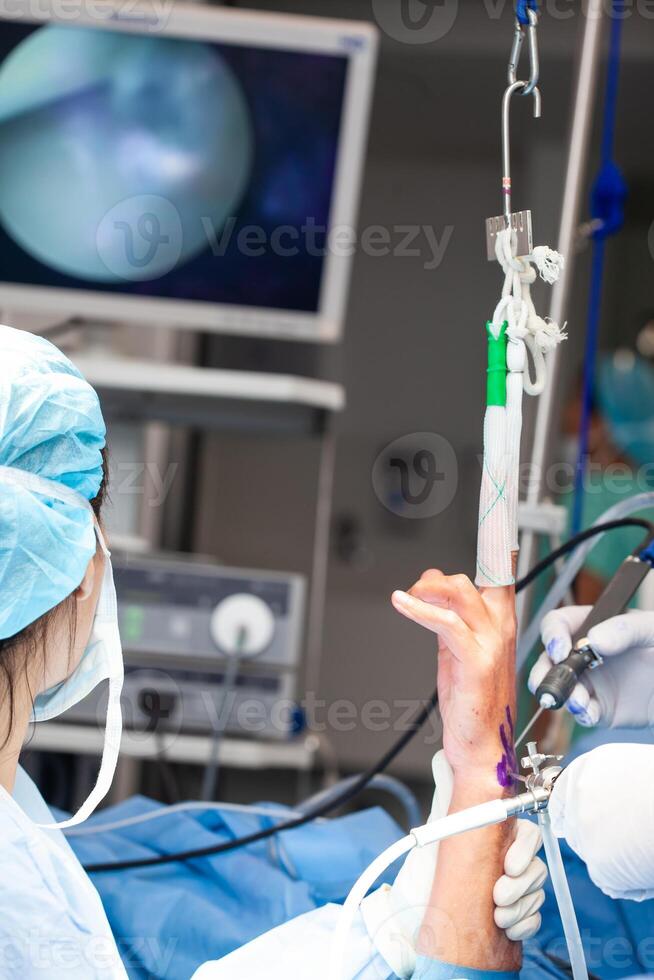 Orthopedic surgeons performing a wrist arthroscopy on a male patient. Female doctor performing a surgery. Orthopedic surgeon. Surgery and insurance concept. photo