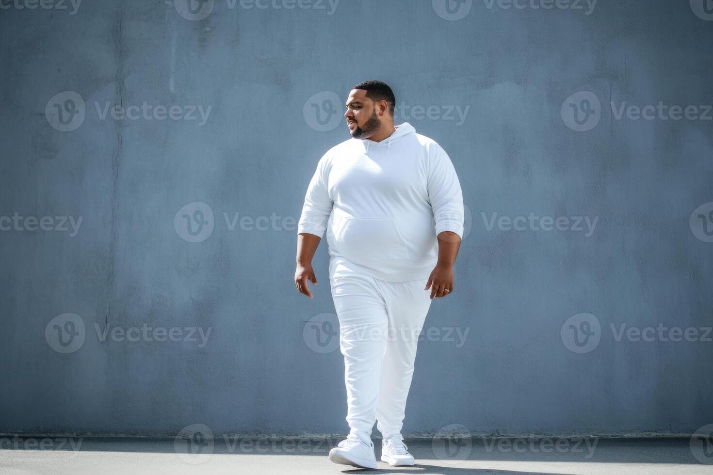 Confident full-figured man strides purposefully in sporty attire against a minimalist backdrop photo