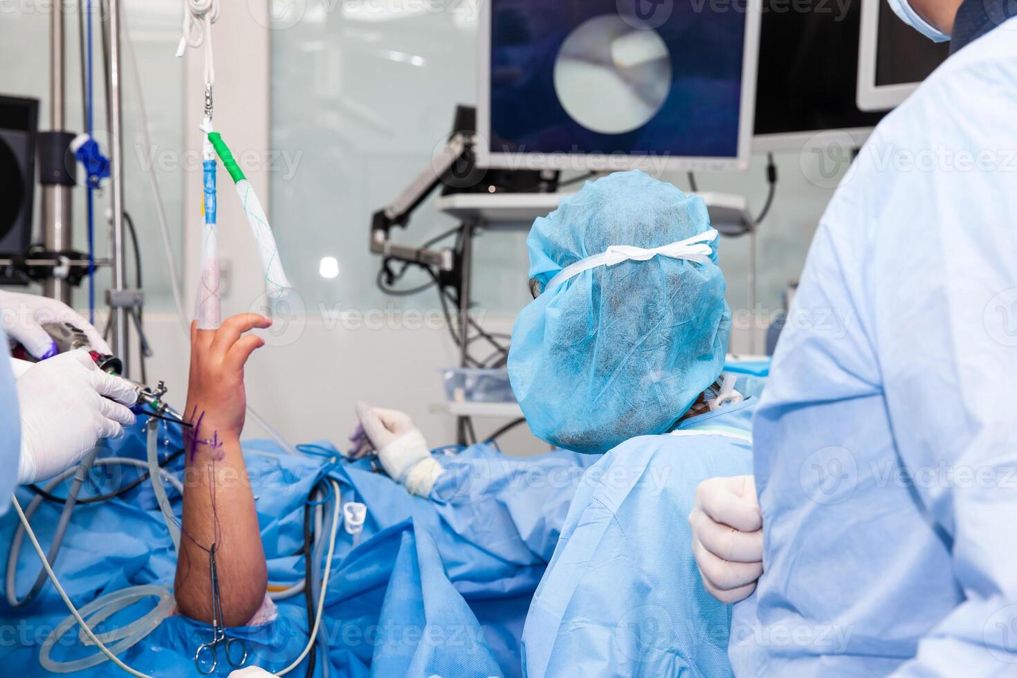 Group of orthopedic surgeons performing a wrist arthroscopy on a male patient. Female doctor performing a surgery. Orthopedic surgeon. Surgery and insurance concept. photo