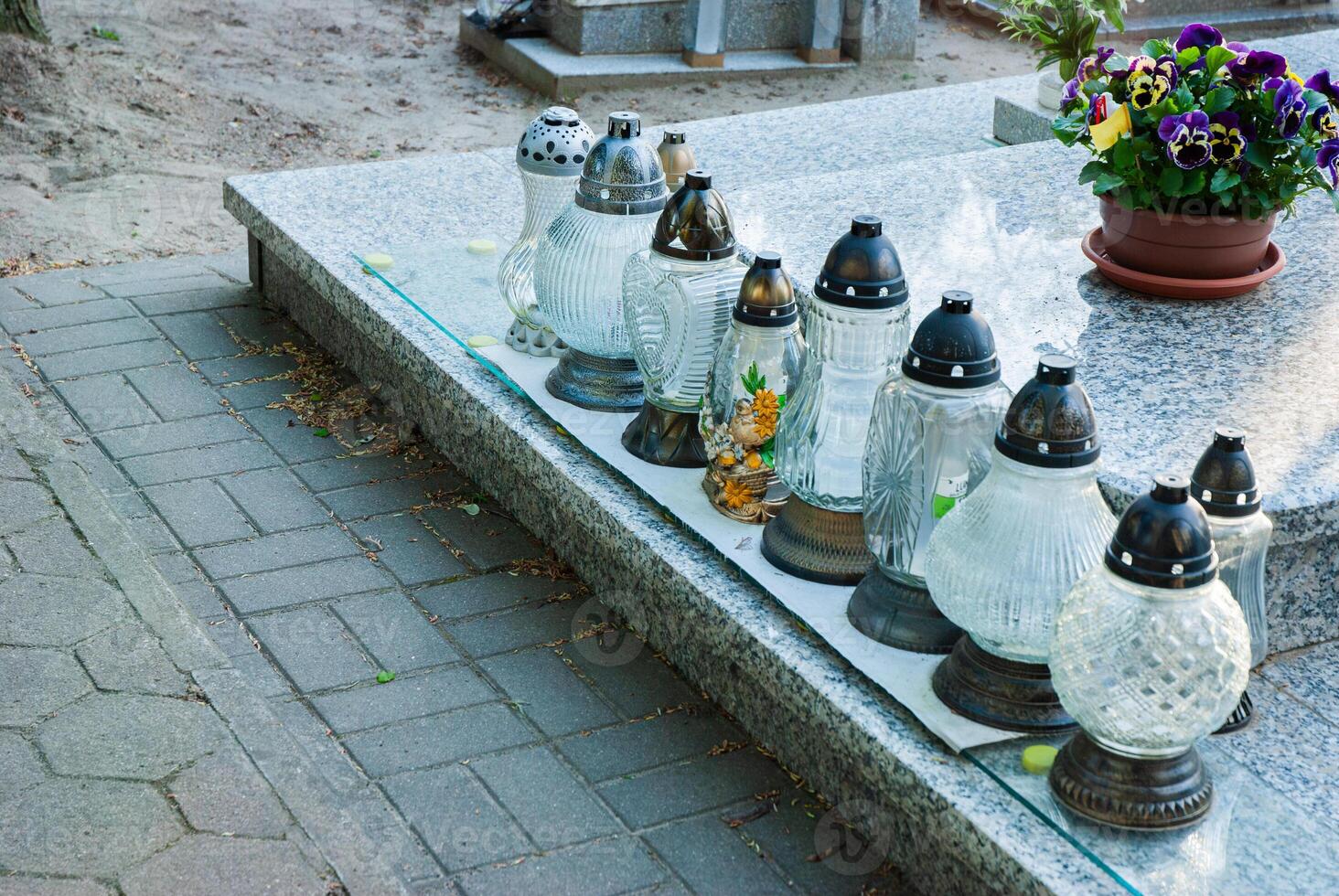 Row of memorial lanterns on granite tomb decorated with vibrant flowers in cemetery setting creating a serene and reflective atmosphere photo