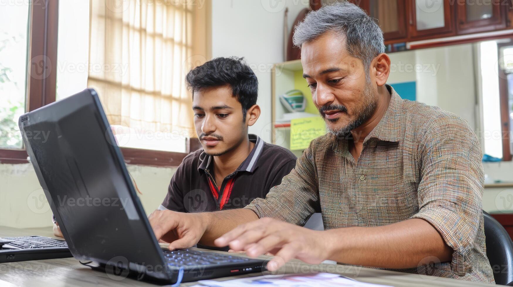 Asian young man and mature man collaborate in office setting, focused on laptop screen, engaging in productive teamwork and knowledge sharing. Mentor worker photo