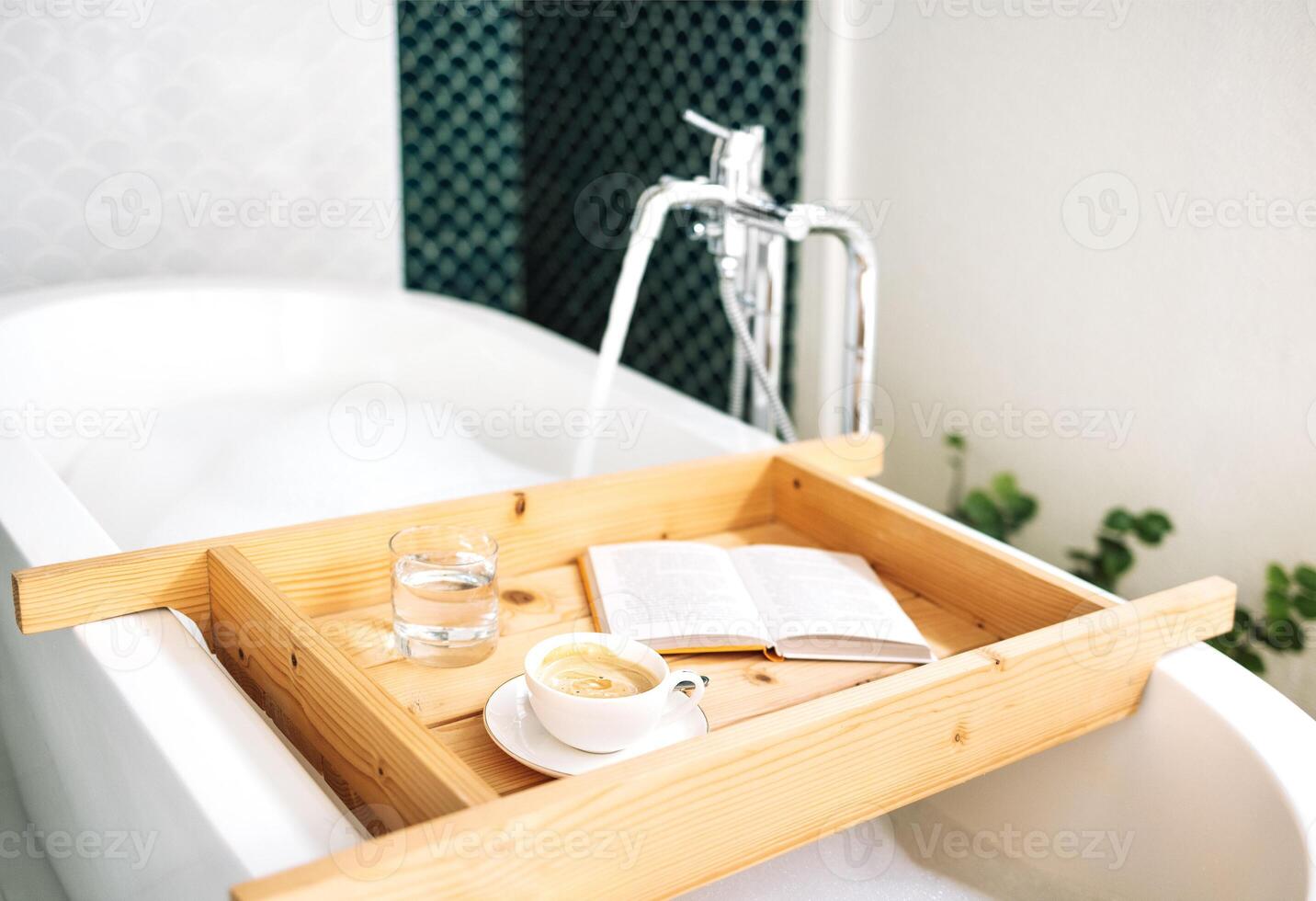 wooden tray is attached to a bathtub filled with hot fragrant water with fluffy foam photo