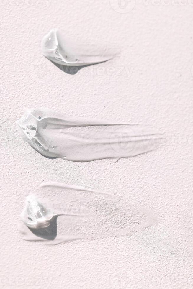 The texture of the cream on a light background. Translucent serum is smeared on the backdrop photo