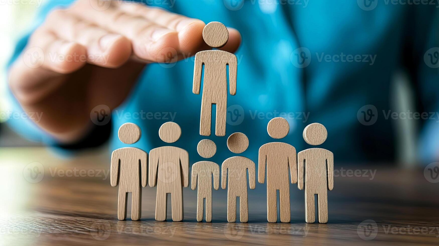 Wooden figures representing teamwork and leadership, with one figure elevated above others, symbolizing guidance and support in a collaborative environment photo