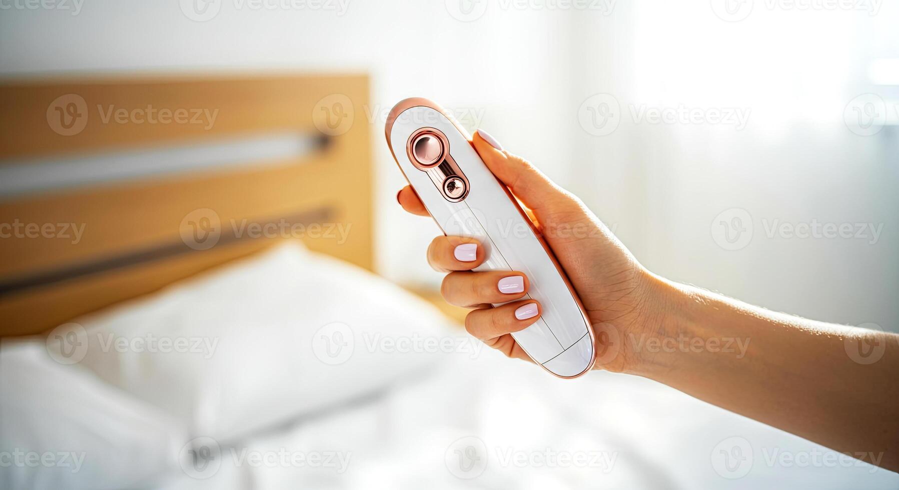 Hand holding a modern handheld garment steamer with a sleek design, positioned against a soft bed backdrop, showcasing innovative fabric care technology and convenience for home use photo