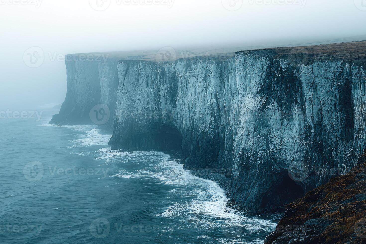 Dramatic Coastal Cliffs Enveloped in Misty Ocean Air photo