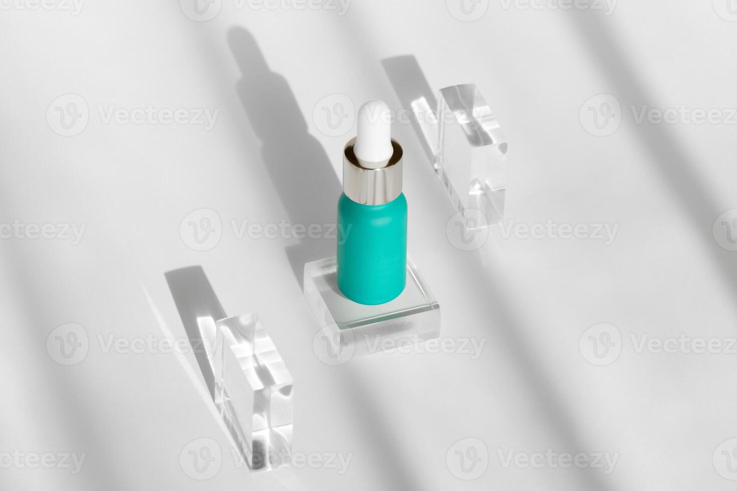 teal serum bottle surrounded by crystal blocks casting elegant shadows on white background photo