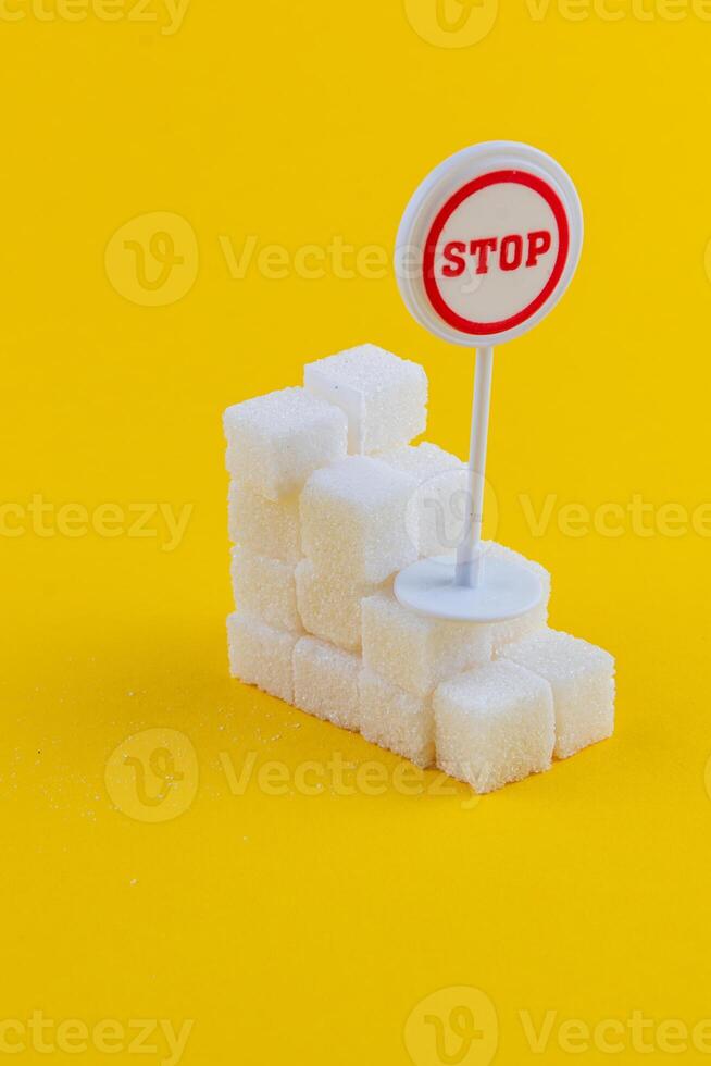 Sugar cubes stacked with a stop sign on a bright yellow backdrop photo
