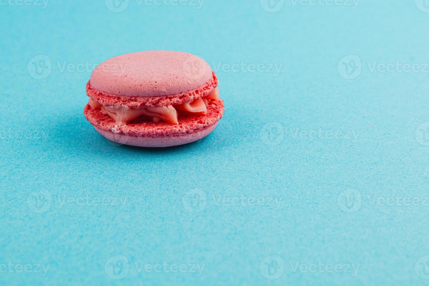 Delicate pink macaroon on a vibrant blue background photo