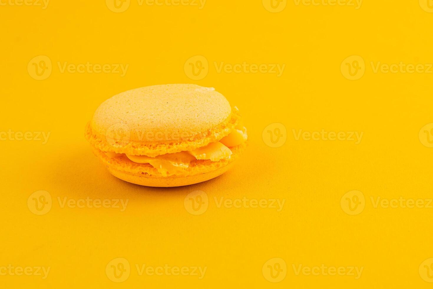 Bright yellow macaroon sits on vibrant yellow background photo