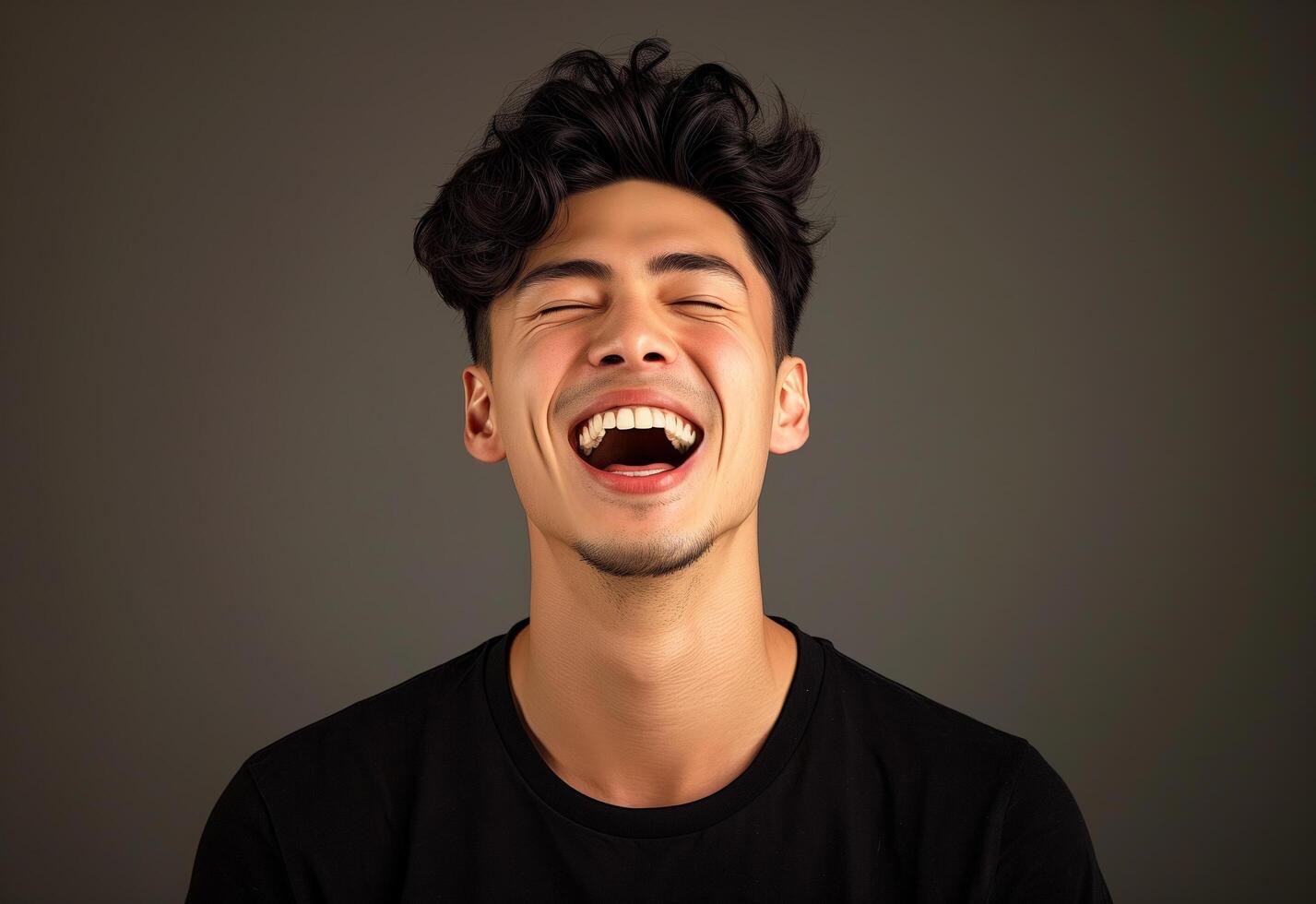 Portrait of a joyful young man laughing with expressive facial features and a dark background photo