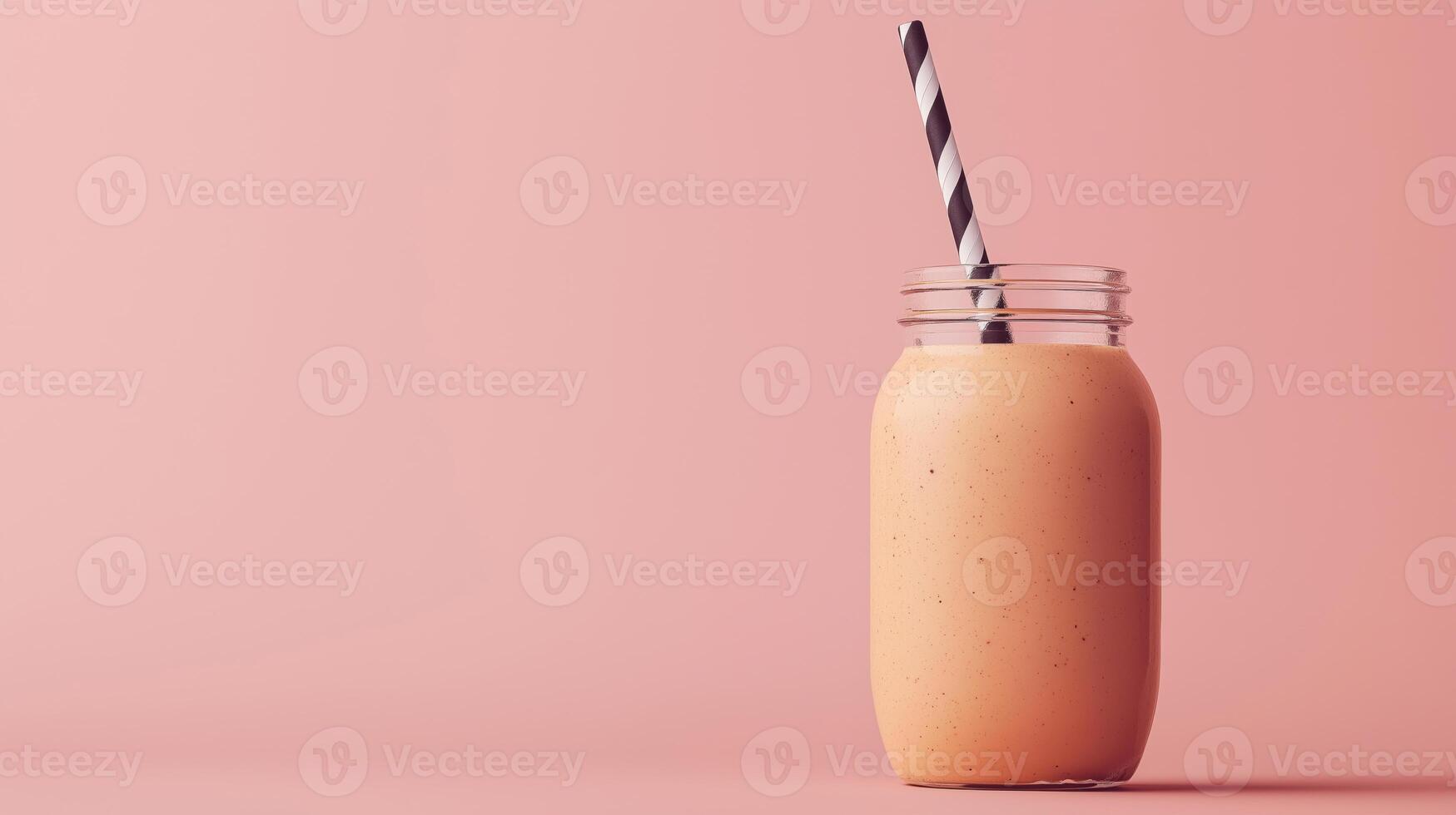 glass jar with a black and white striped straw. The jar is filled with a brown smoothie or milkshake. The background is a light brown color photo