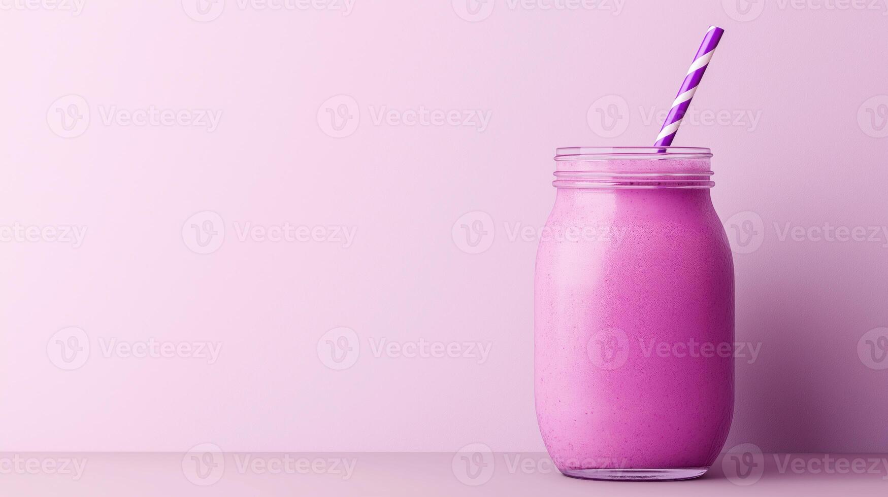 glass jar with a violet and white striped straw. The jar is filled with a purple smoothie or milkshake. The background is a light purple color photo