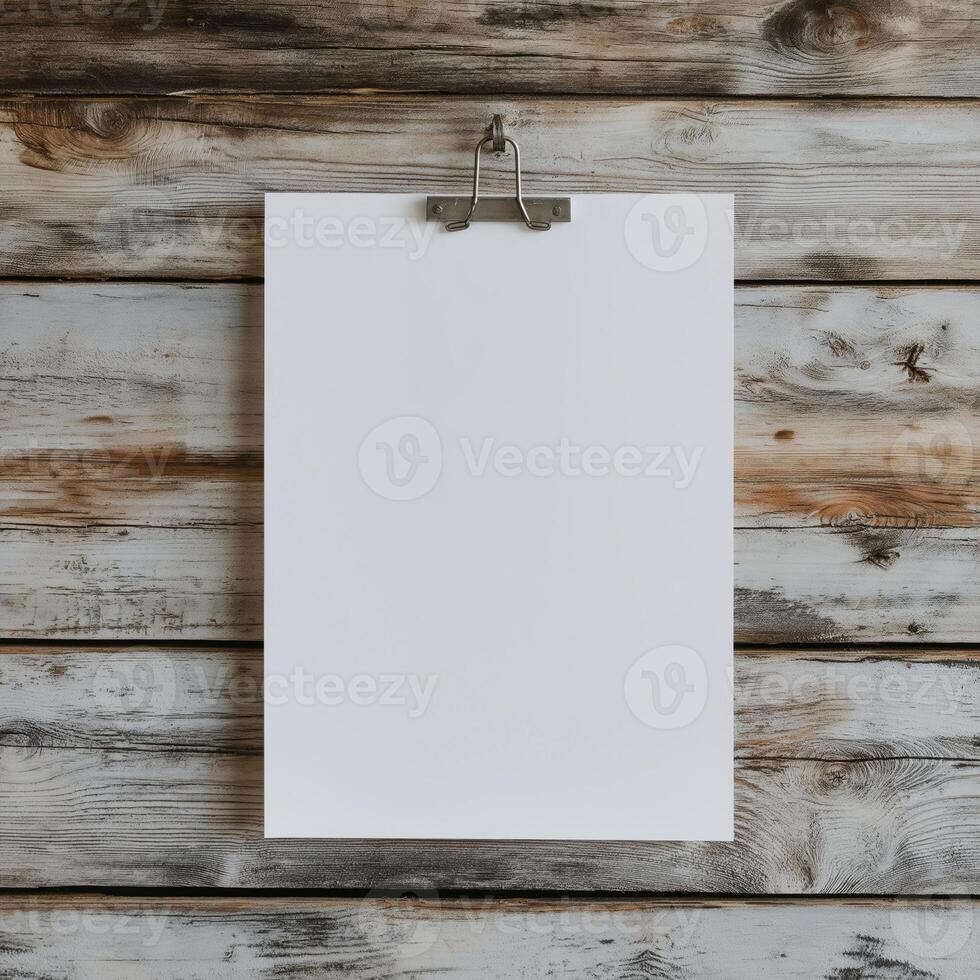 blank white paper hanging on a wooden wall. The paper is hanging from a metal hook on the wall photo