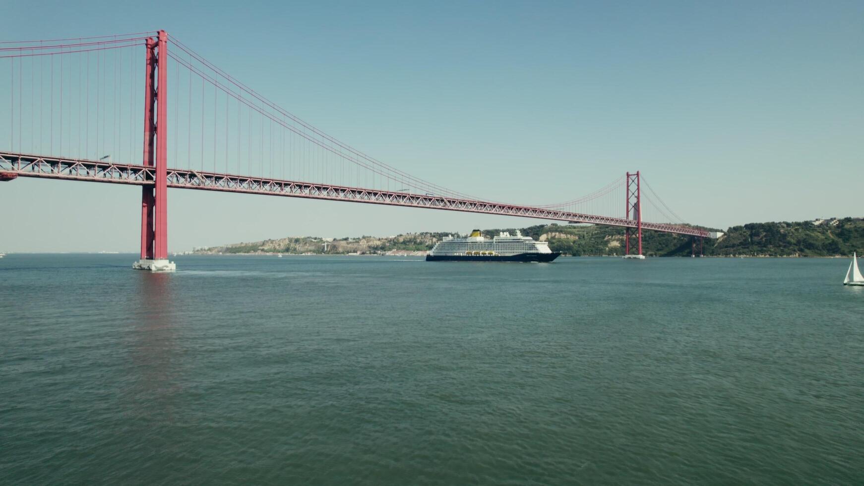 Lisbon, Portugal, 2025 - The ship sails under a red suspension bridge on a wide river in Portugal. Yachts and sailboats sail on the river. Drone . - Yachts photo