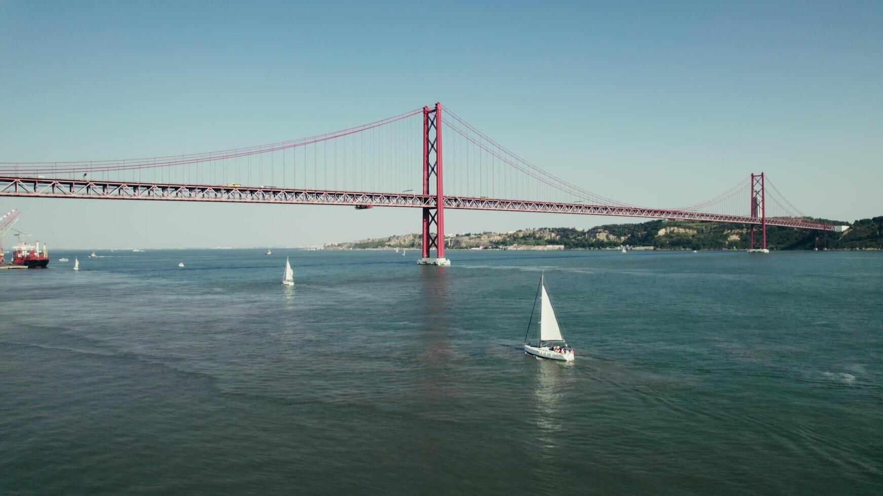 Lisbon, Portugal, 2025 - The drone flies over the wide Tagus River in Portugal, with a red suspension bridge connecting Lisbon and Almada - Almada photo