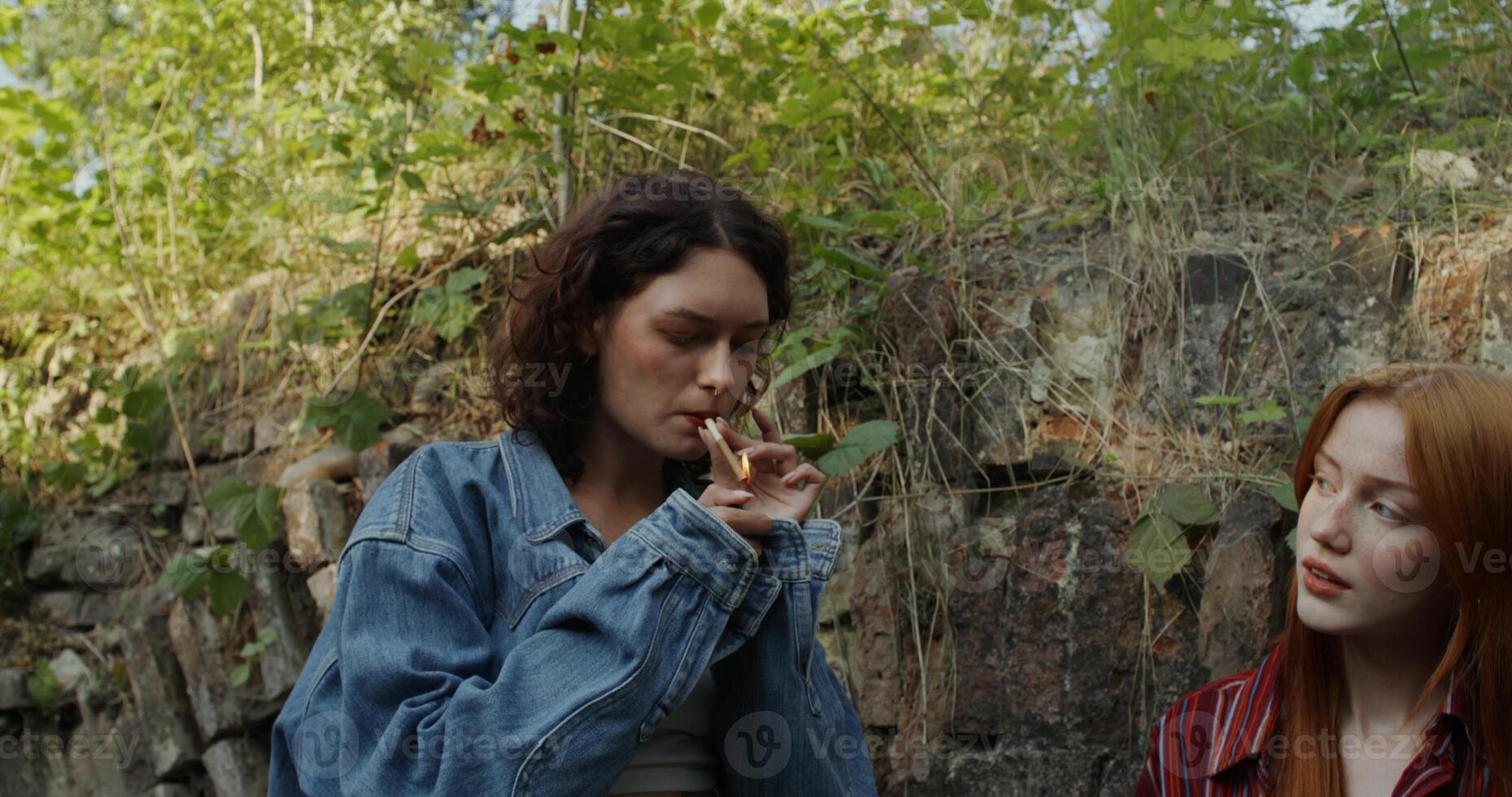 Two friends are smiling and talking standing near a ruined historical building. They smoke. A sunny summer day photo
