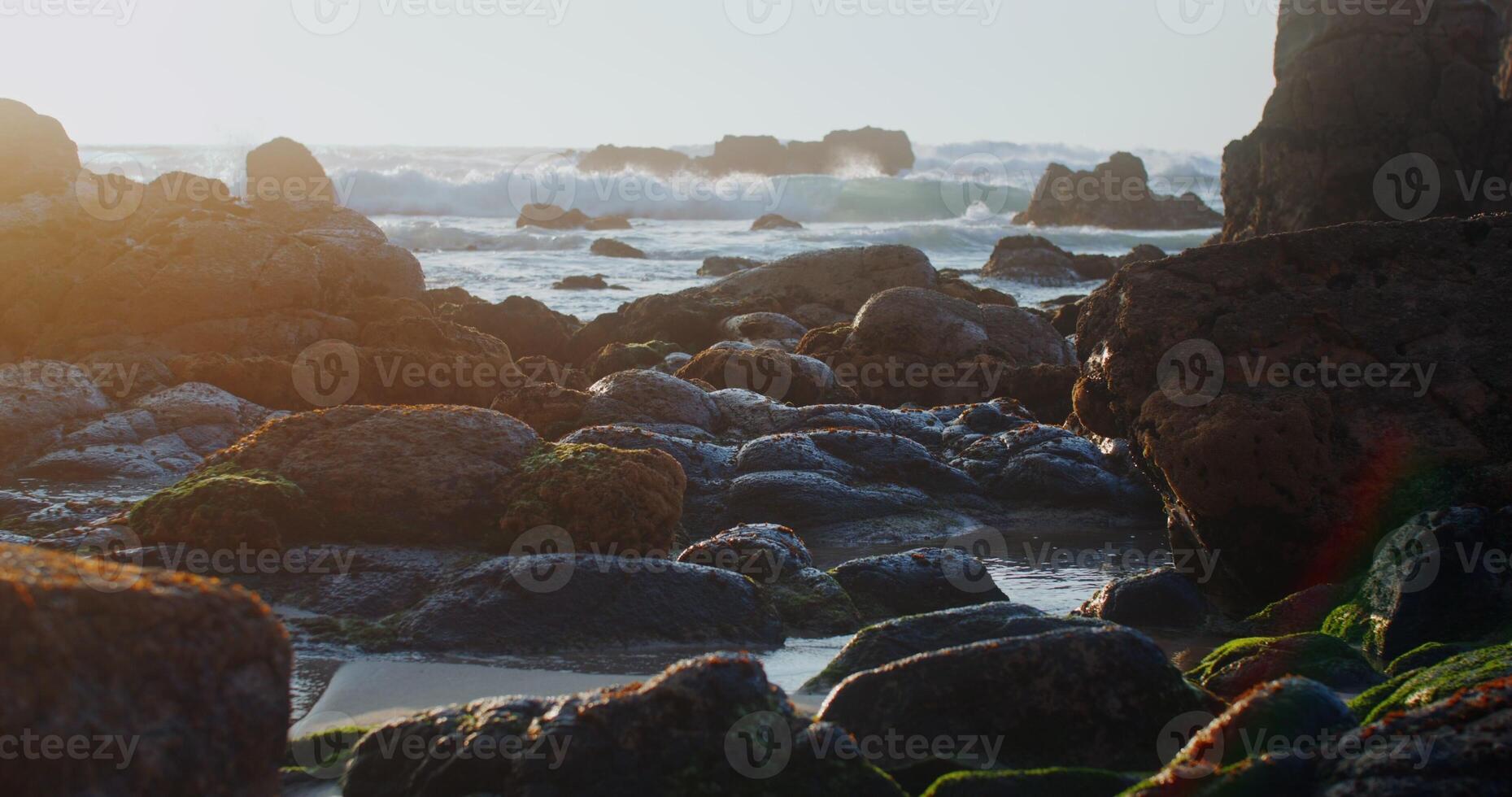 sea waves crash against the rocks at sunset photo