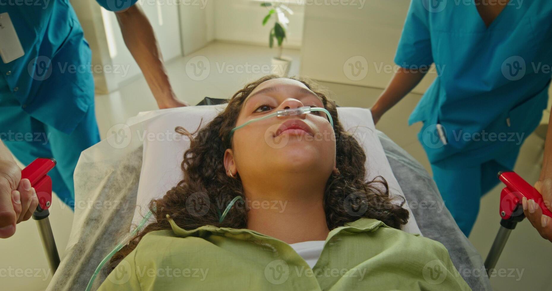 Medics are taking a woman on a gurney along the hospital corridor. The oxygen tube is in her nose photo