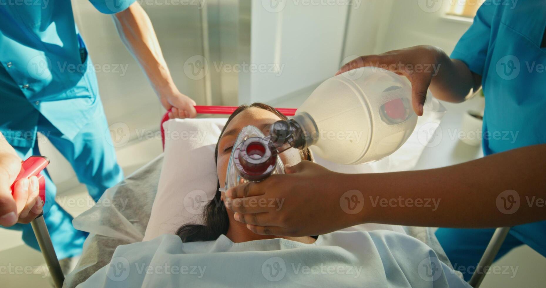 Medics are taking a woman on a gurney. A nurse holds an oxygen mask photo