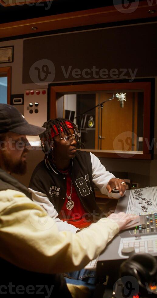 Listening to the song after recording in the studio. The sound engineer and the performer photo