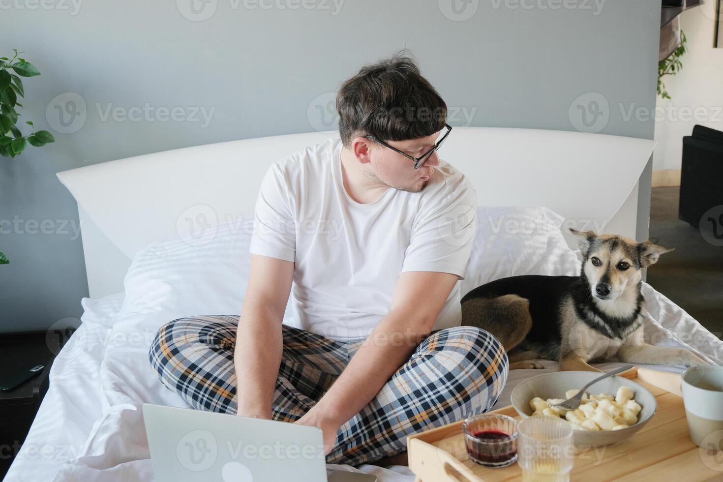 Young man waking up and having breakfast with dog photo