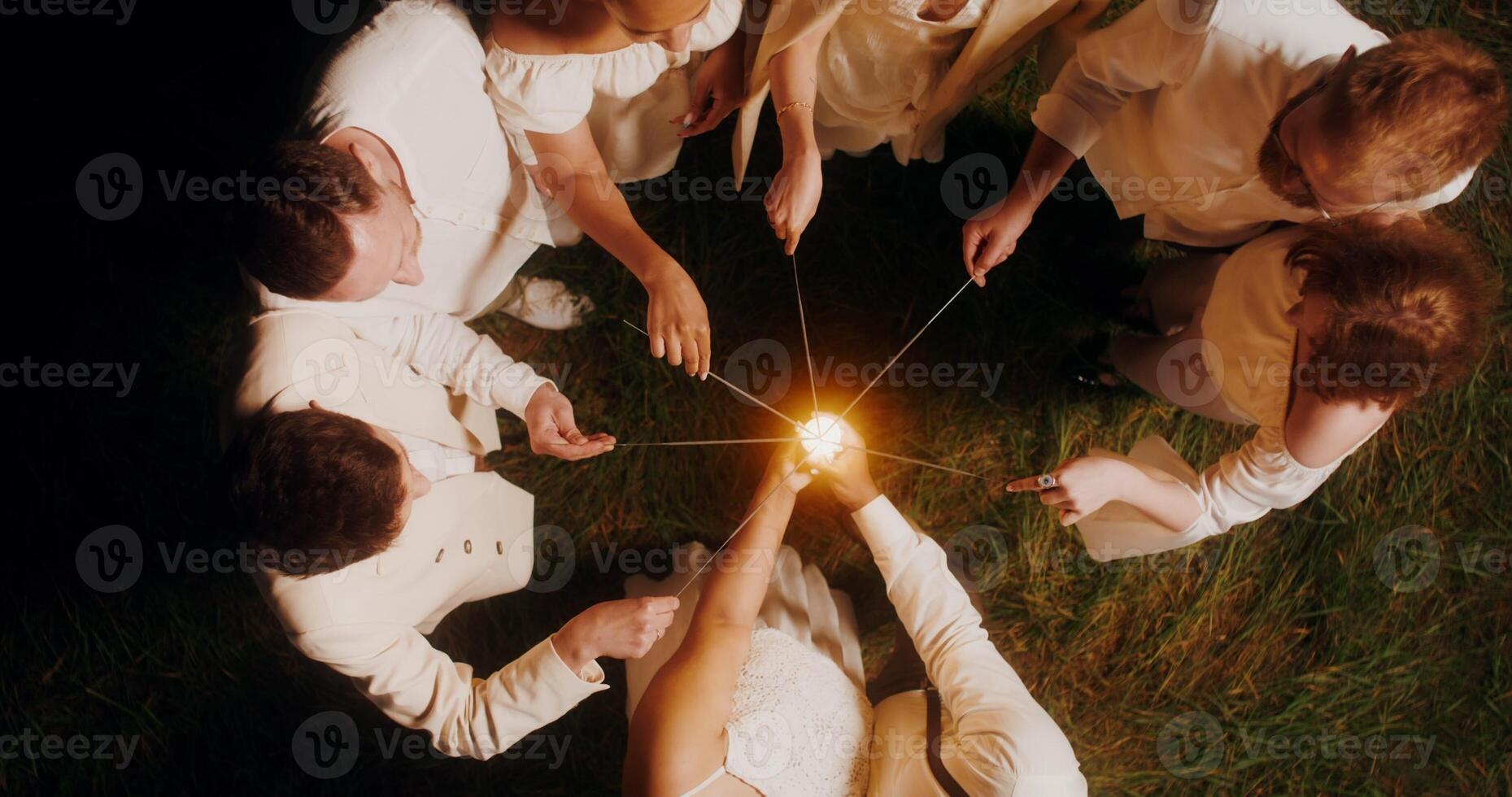 Top view of the guests lighting sparklers and start dancing with them around the bride and groom, wedding concept photo