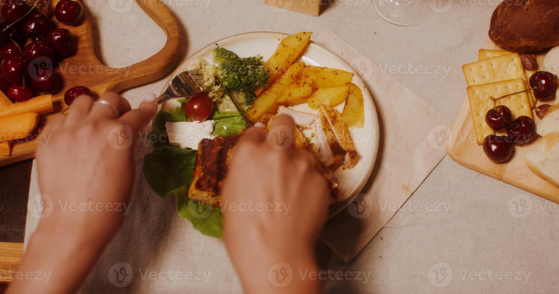 Woman's hands use cutlery cutting steak with vegetables. A woman is sitting at a festive table, a close-up of her hands photo