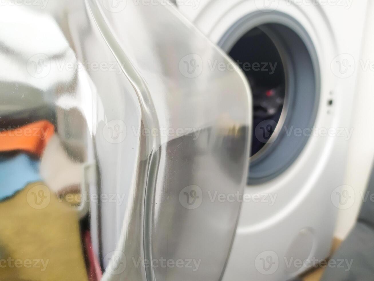 Open washing machine door with blurred laundry inside. Home appliance for cleaning clothes, symbol of chores, domestic work. Useful for cleaning services promotion. photo