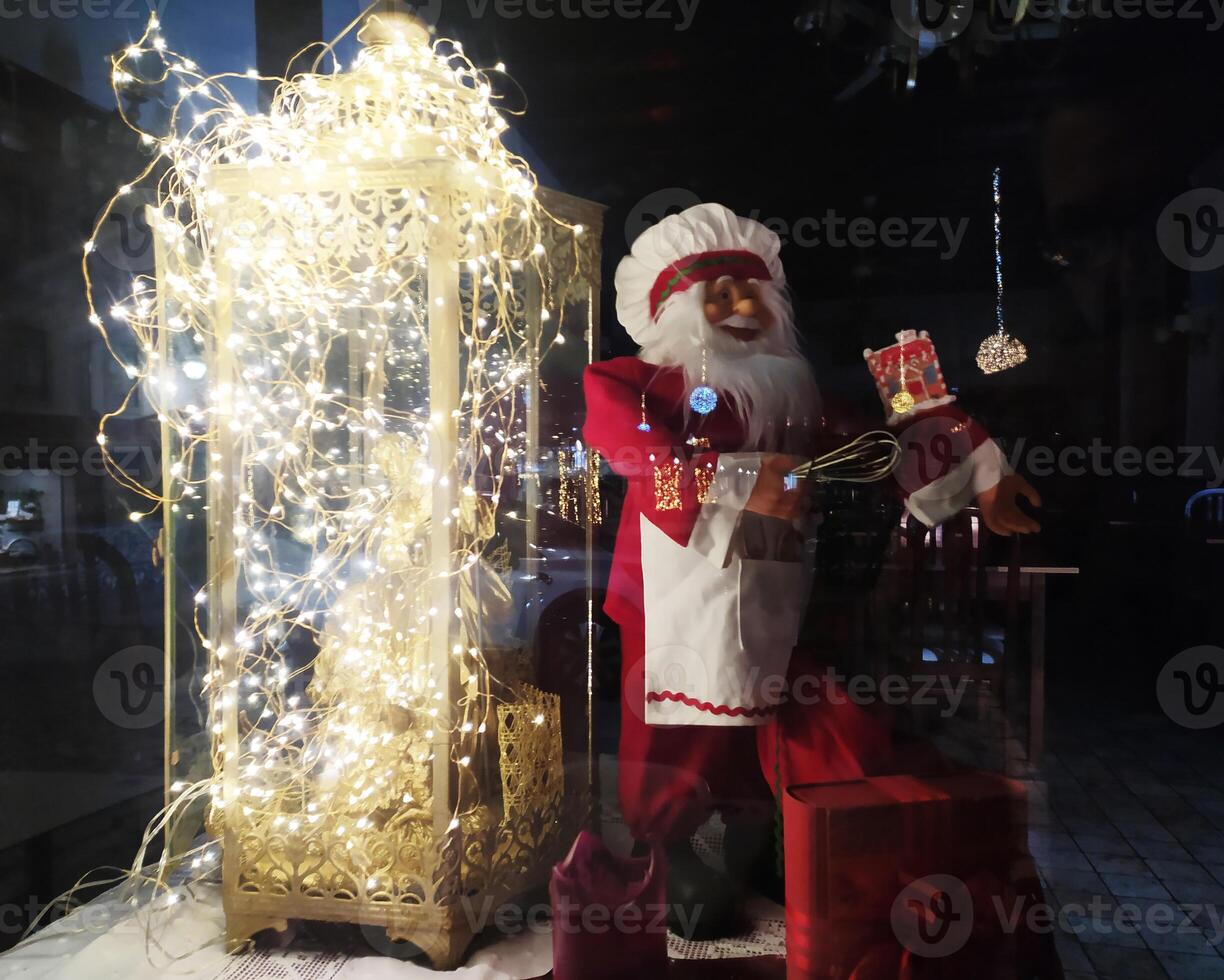Enchanting Christmas display featuring a Santa chef figurine near a luminous lantern adorned with fairy lights. Perfect for holiday greeting cards, festive websites, or winter season advertising. photo