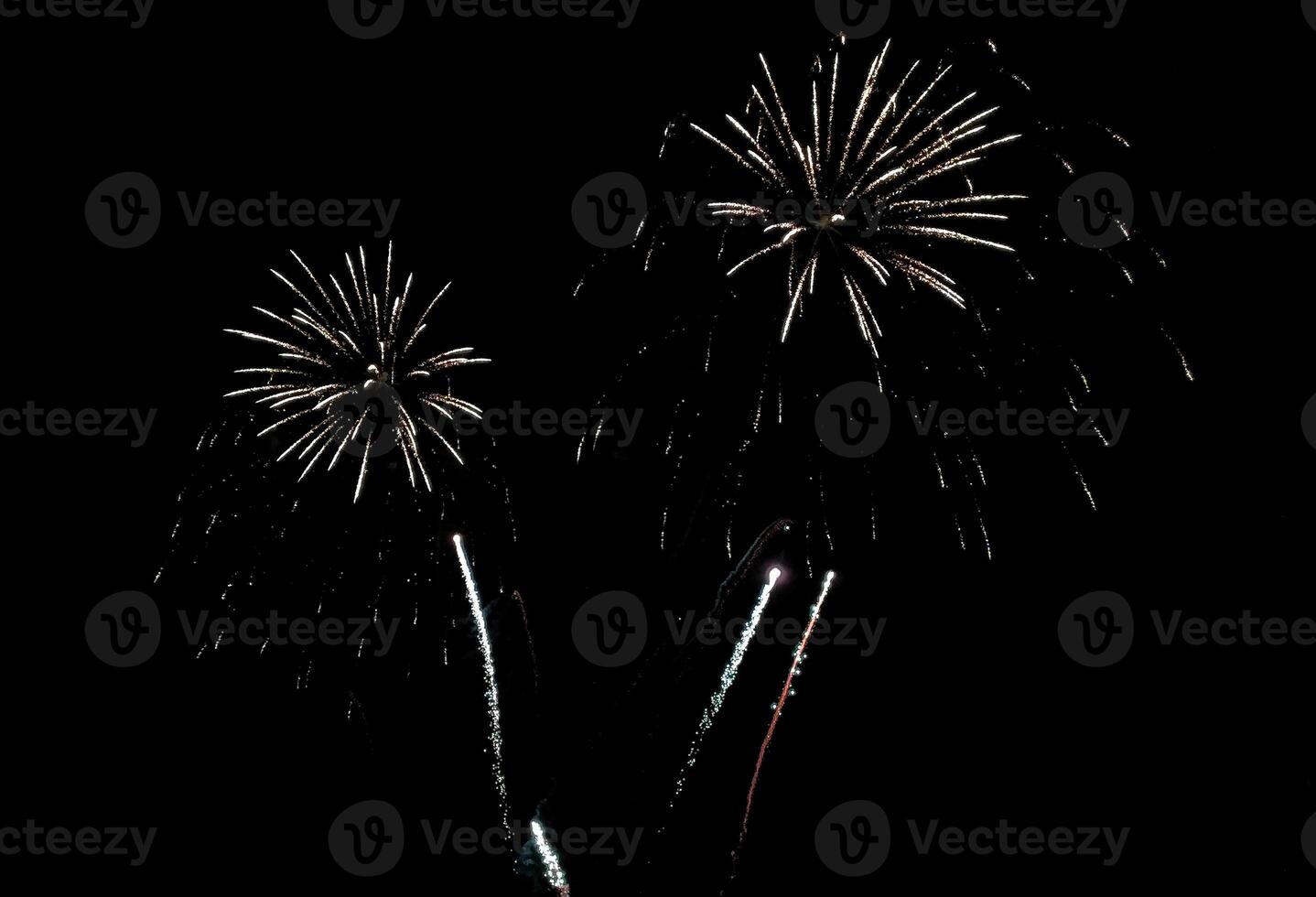 Stunning fireworks display against a deep black night sky. Three vibrant bursts illuminate the darkness, creating a dramatic and festive scene. photo