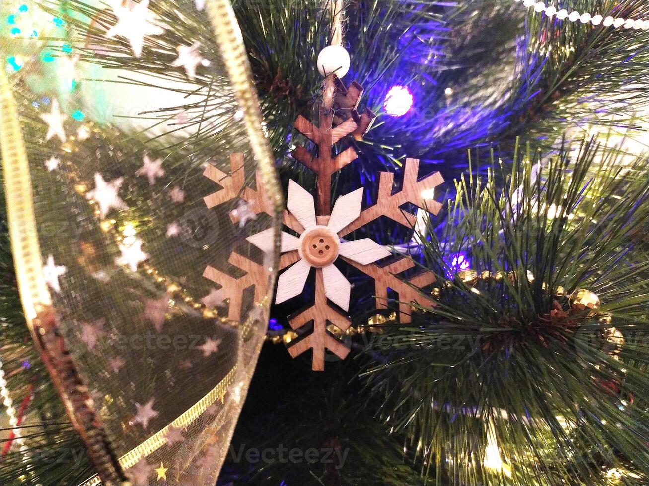 Close-up of a rustic wooden snowflake ornament hanging on a decorated Christmas tree. photo