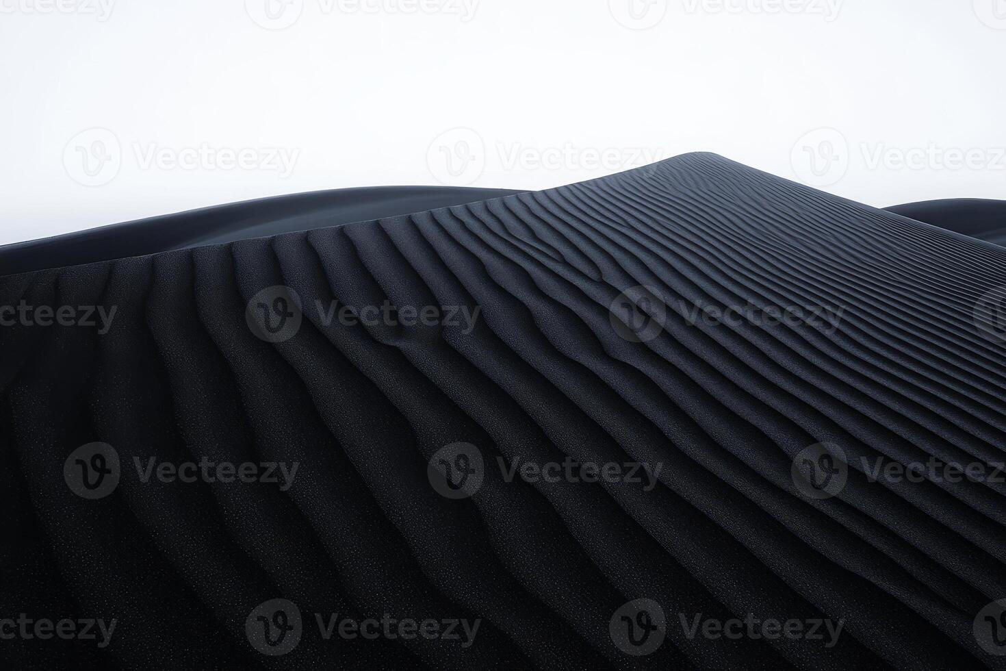 Experience the striking beauty of black sand dunes at twilight featuring smooth, flowing lines accentuated by the soft light above photo