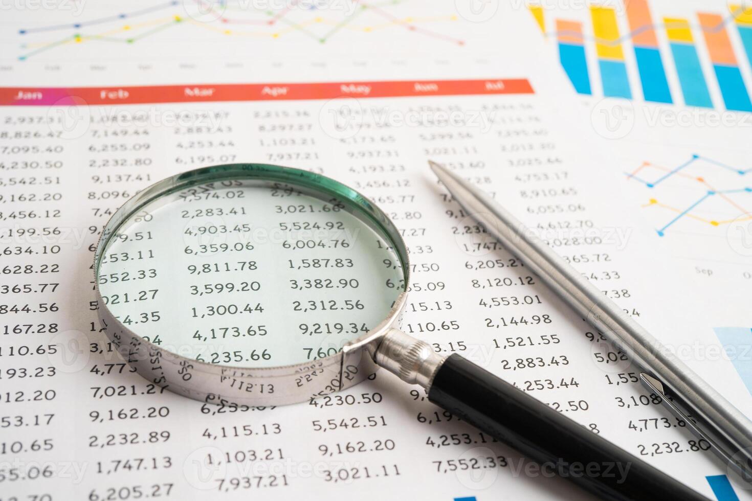Magnifying glass on spreadsheet and graph paper. Financial data economy photo