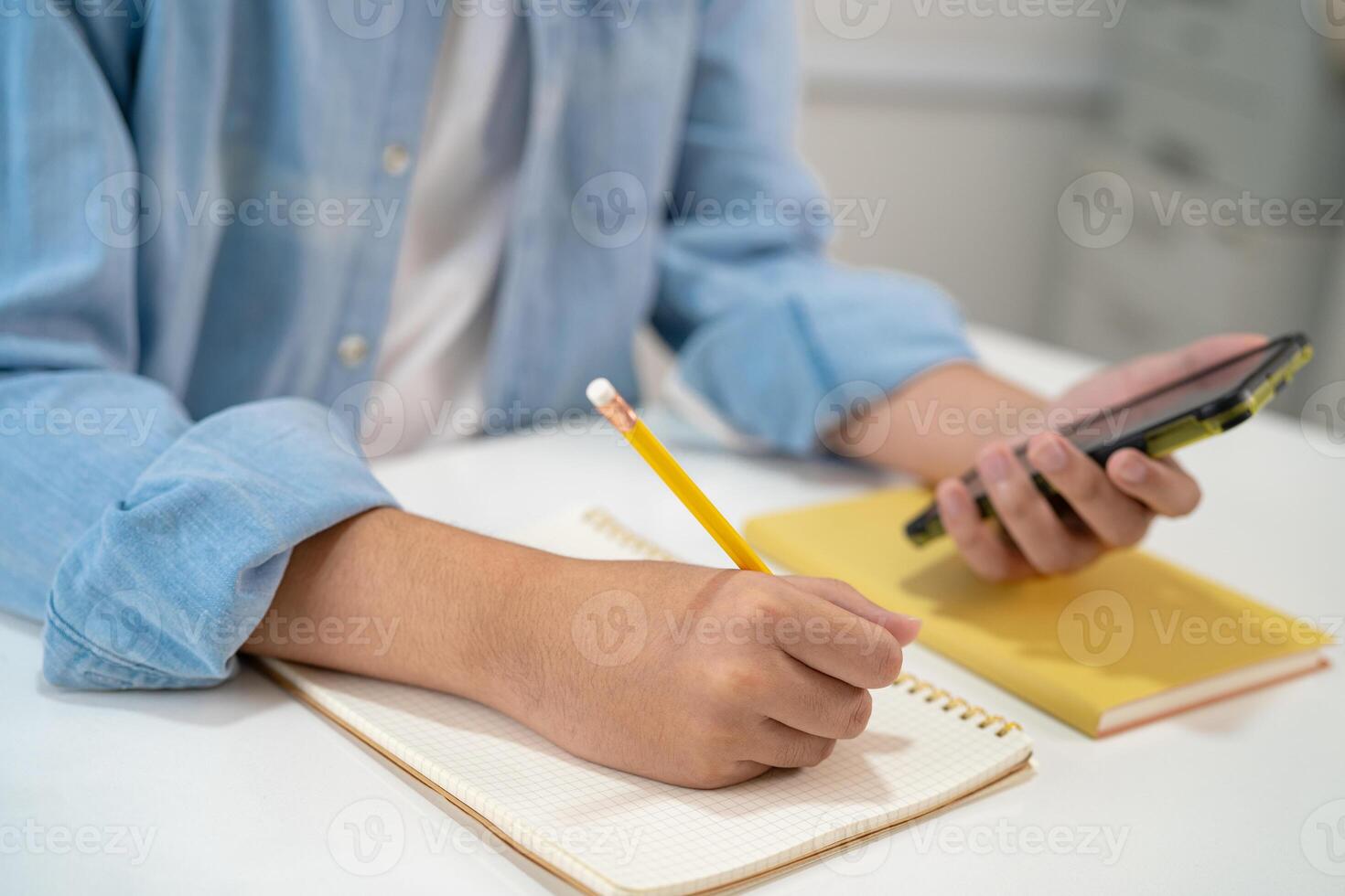 Teenage write in notebook and use mobile phone search data online to online learning education. photo