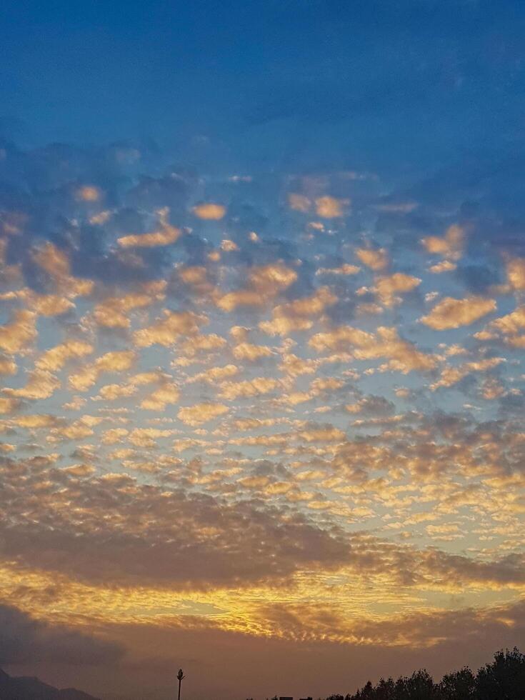 A sunset adorned with fluffy clouds, where the sunshine radiates and casts a warm, inviting glow across the horizon. photo