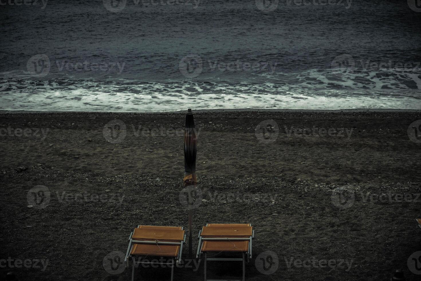 deck chair alone on the sandy beach by the sea on a sad and gloomy day photo