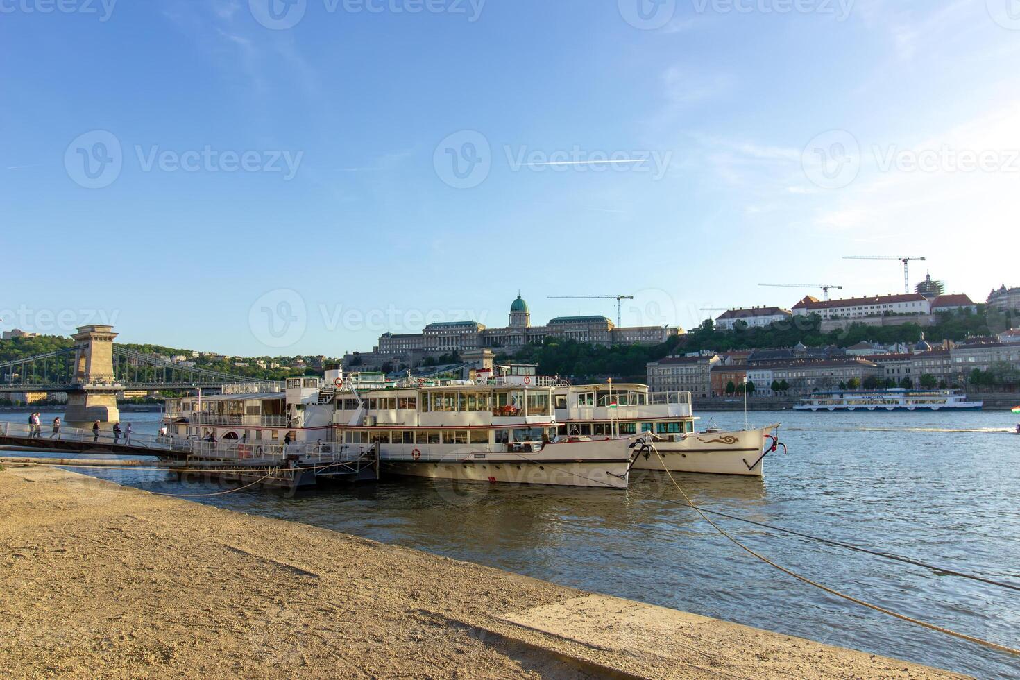 Cruise boats docked on the Danube River in Budapest with view of Buda Castle and Chain Bridge in the background, photographed on April 14, 2024 photo