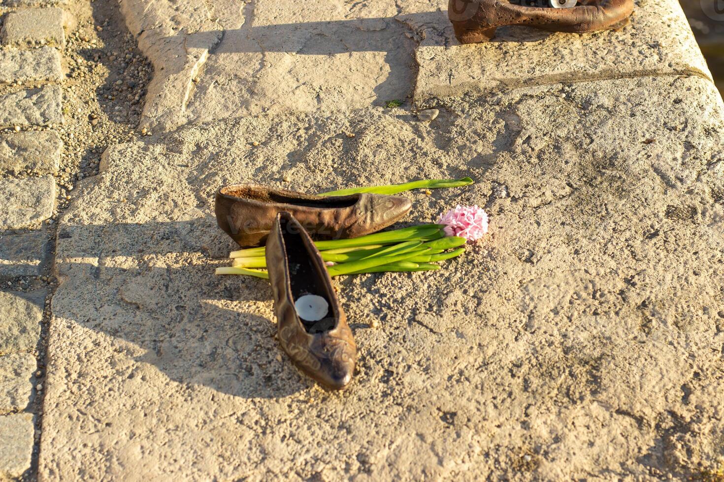 Close-up and wide views of Shoes on the Danube Bank memorial in Budapest with bronze shoes, flowers, and candles along the riverside promenade photo