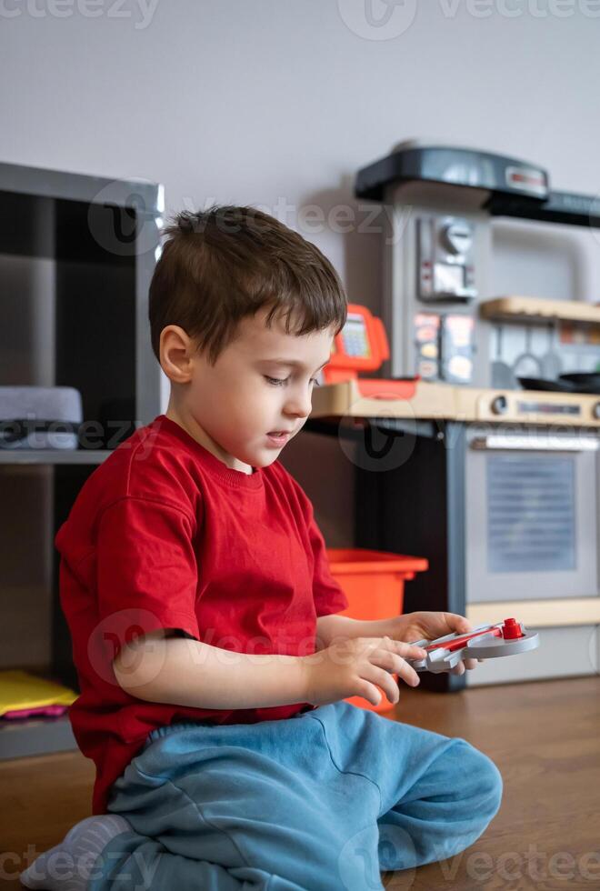Little boy playing with toys while sitting on the floor at home. Early development, imagination, and childhood learning in a family environment. Child psychology, home life, and early education themes photo