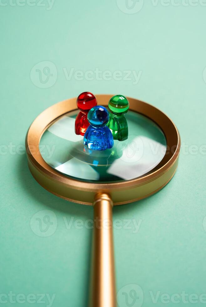 Figures of people standing on a magnifying glass. Concept study of groups of society and consumers. Marketing. Recruitment. Segmentation. Market segments, and workforce demographics photo