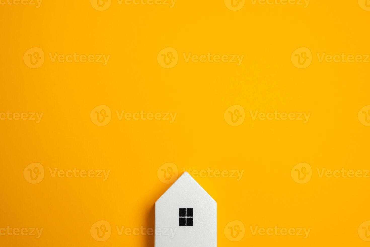 A small house figure appears to be peeking out of the frame against a yellow background. Real estate and housing. Purchase, sale and rent. photo