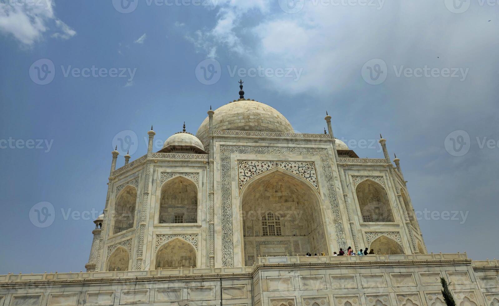 A closer angle of the Taj Mahal, taken from one side, highlighting the intricately carved marble arches and domes. This perspective gives a majestic feel and shows the building's elevated platform. photo