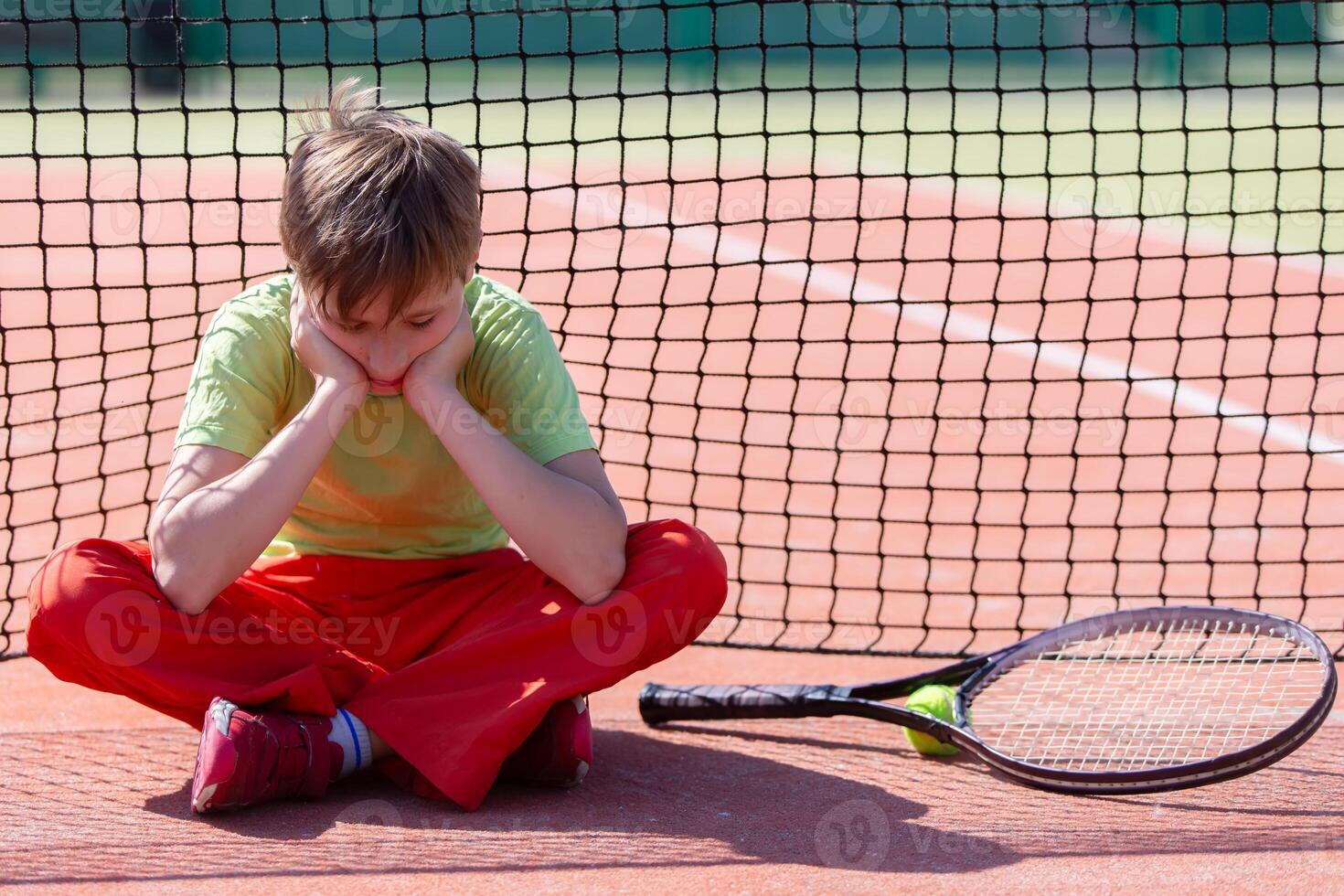 The child sits at the net with a racket. H photo