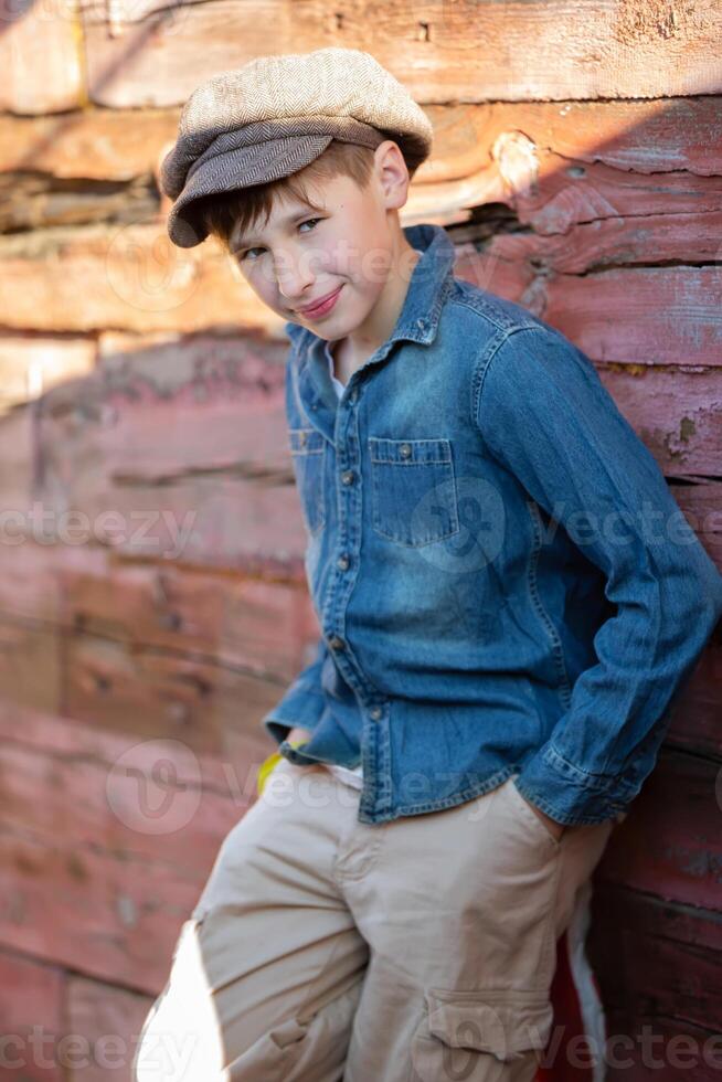 Portrait of a vintage village boy in a cap and denim jacket. Beautiful child from the village. photo