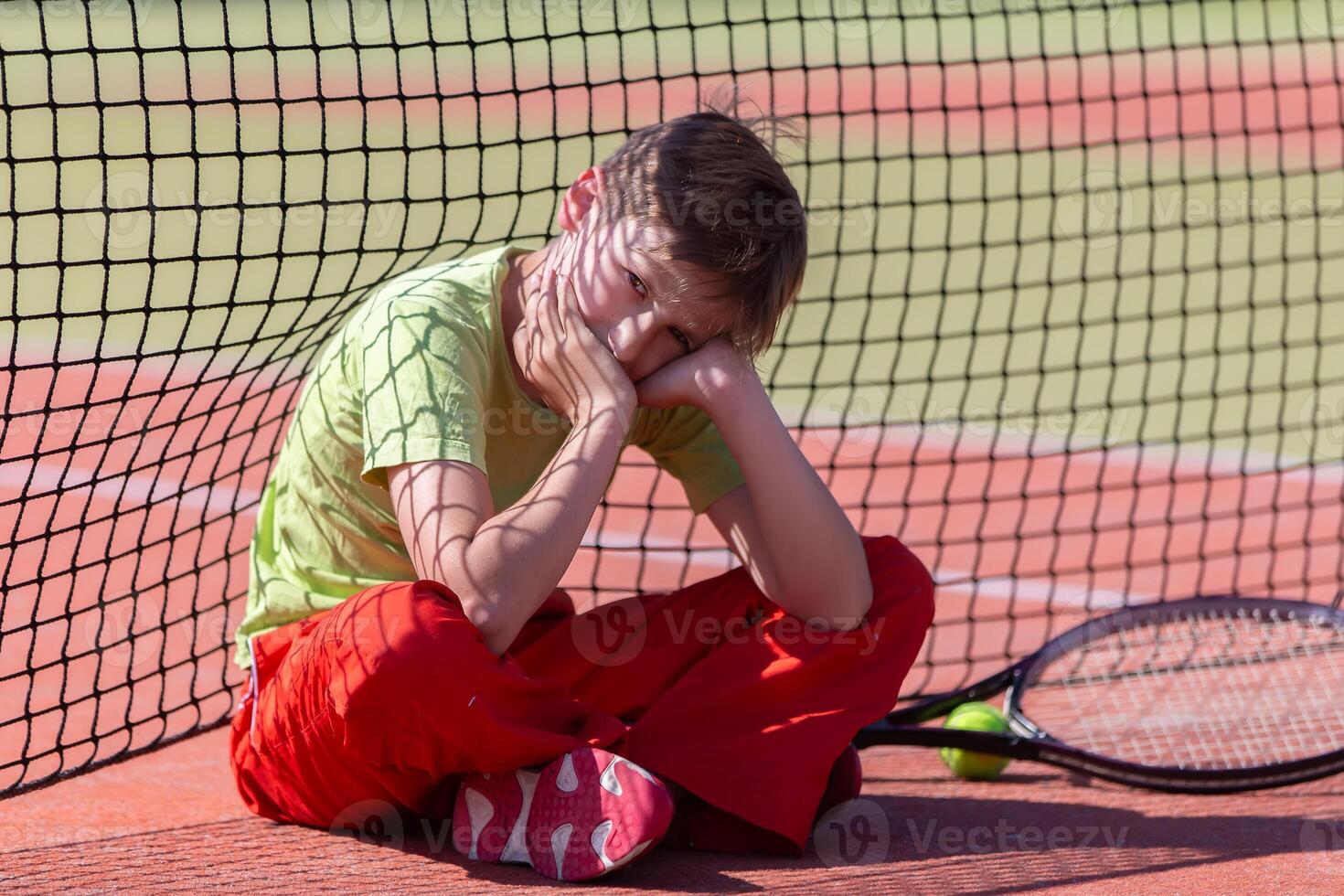 The child sits at the net with a racket. photo