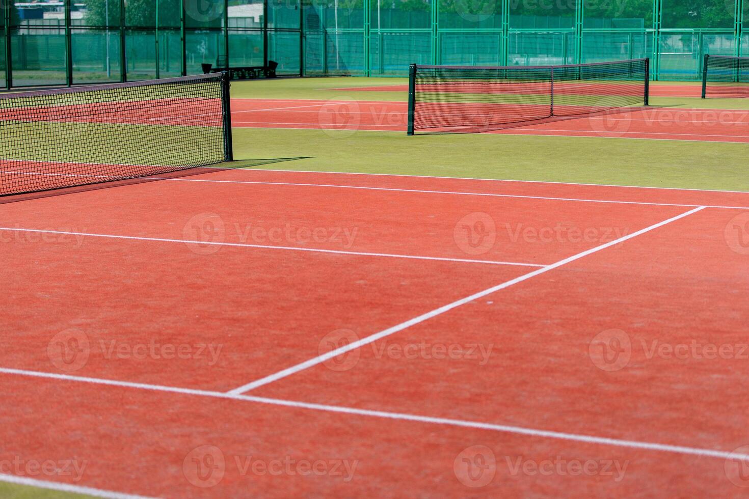 The tennis court is empty with a net and a fence photo