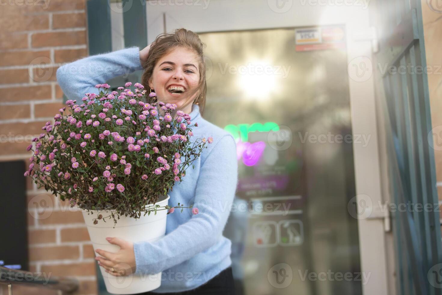 A beautiful girl is holding a large bouquet of flowers and smiling photo