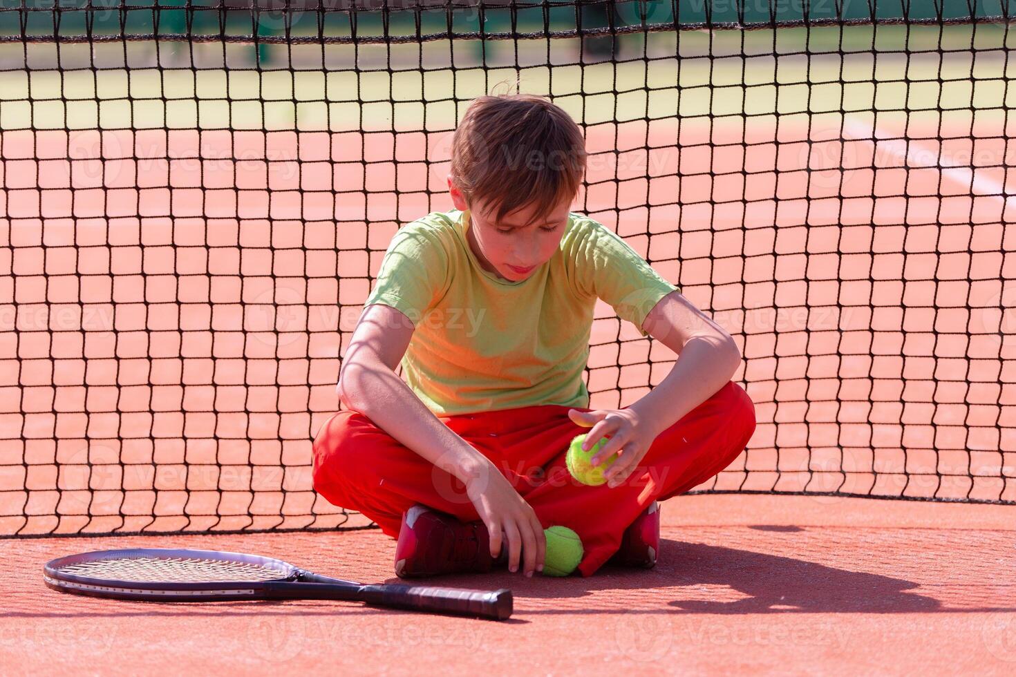 The child sits at the net with a racket photo