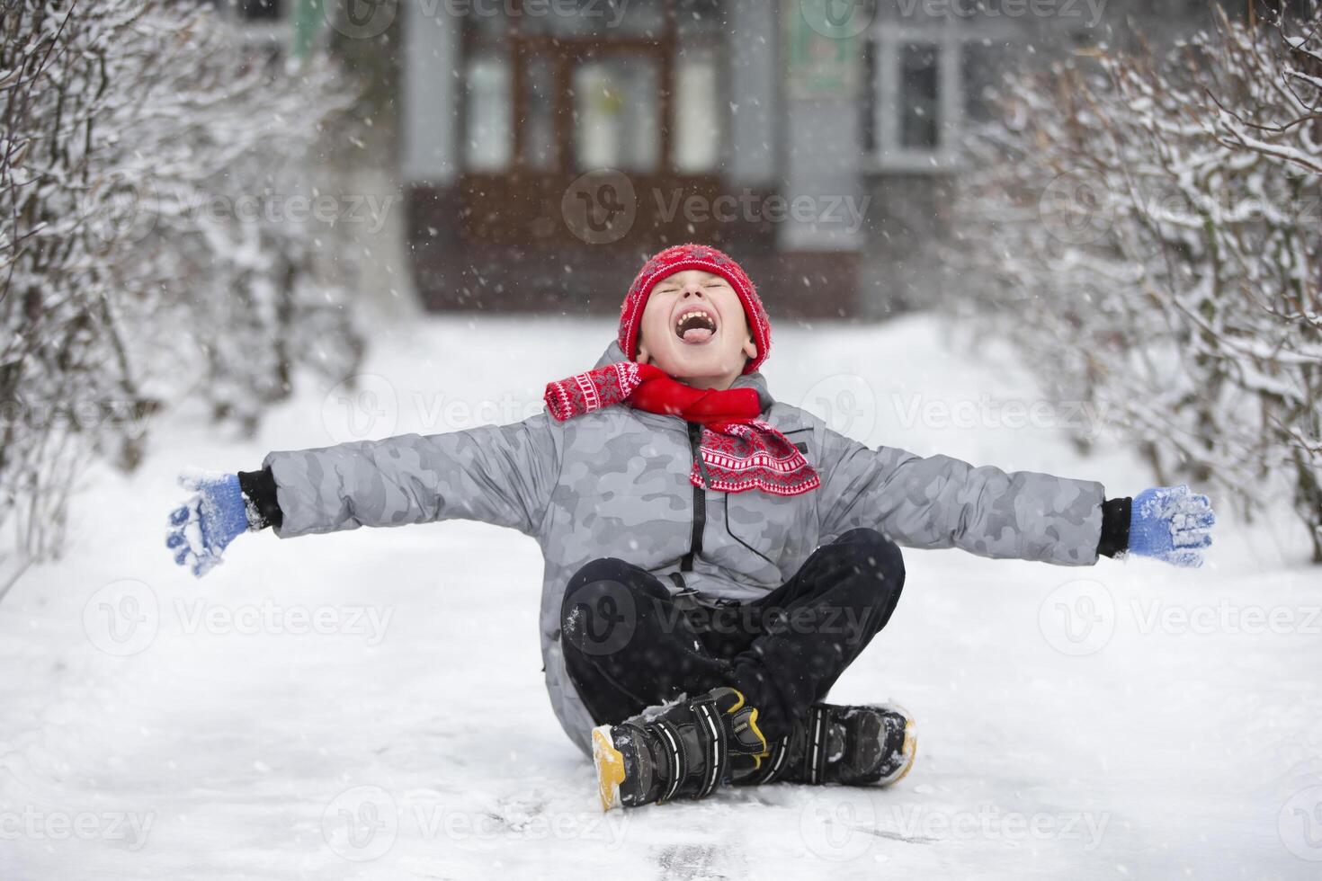 Happy boy catches snowflakes with his mouth. The child rejoices in winter and the first snow. photo